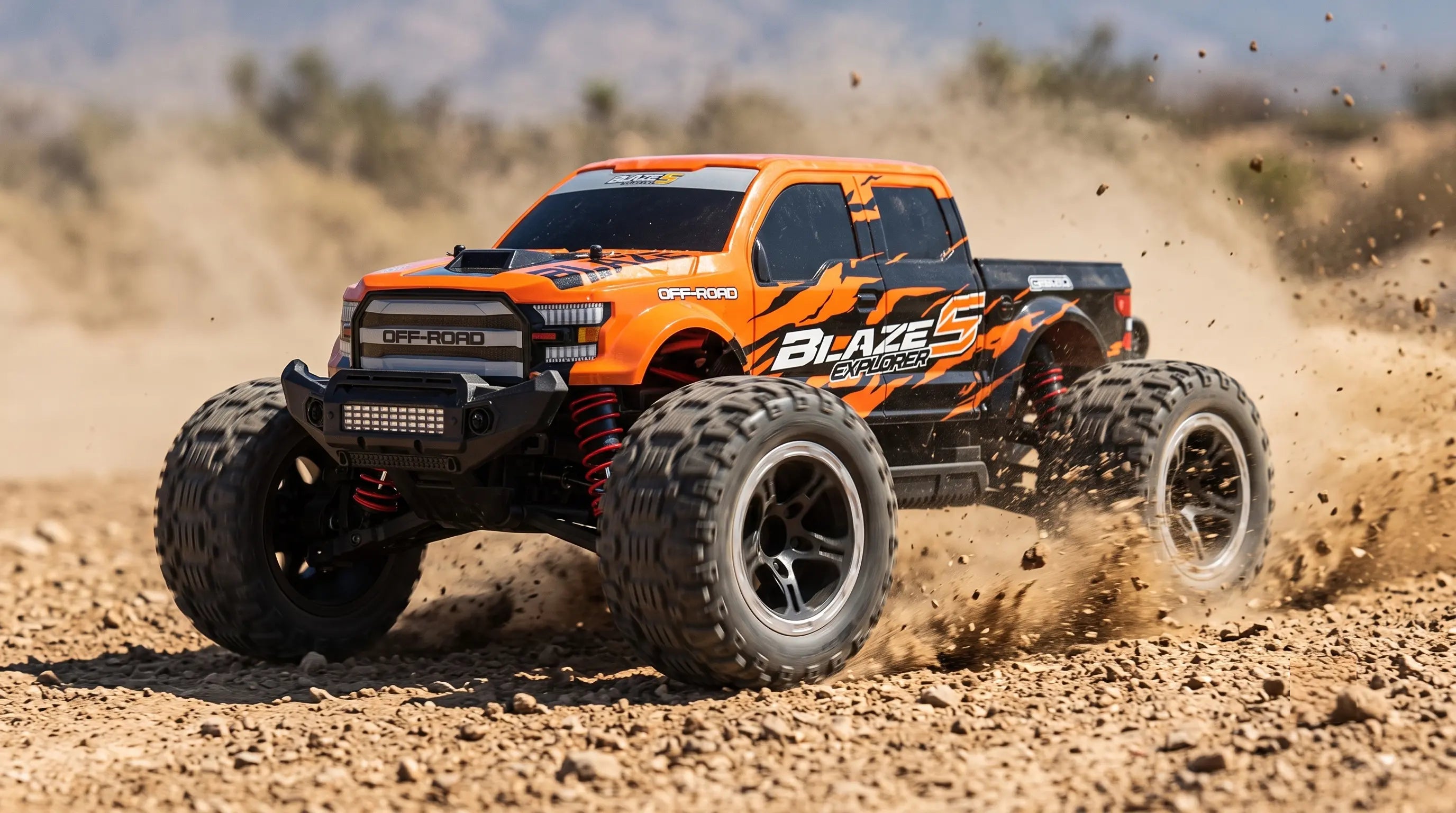 An orange RC monster truck kicking up dirt.